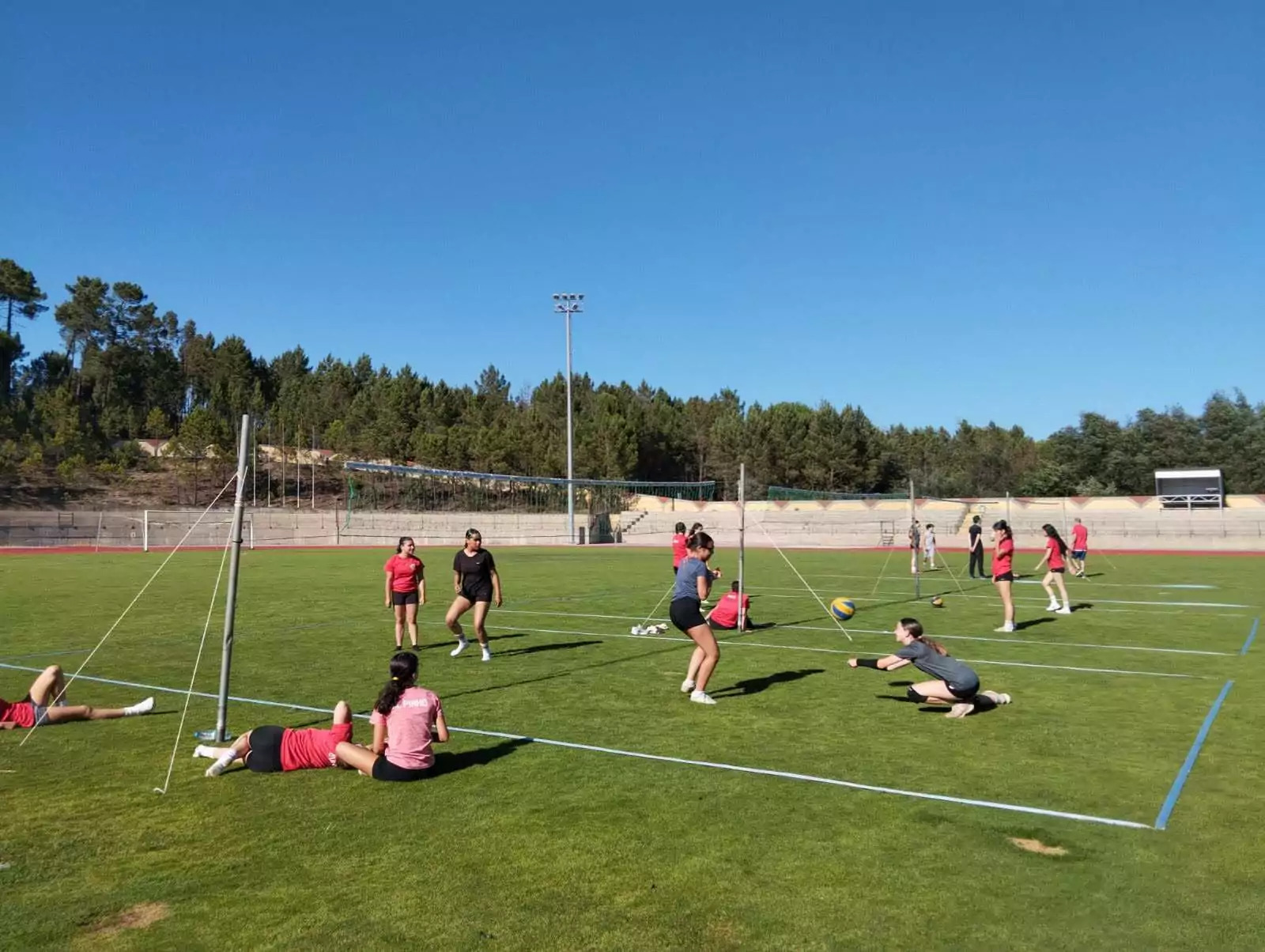 Jovens praticam jogos e exercícios no campo de relva