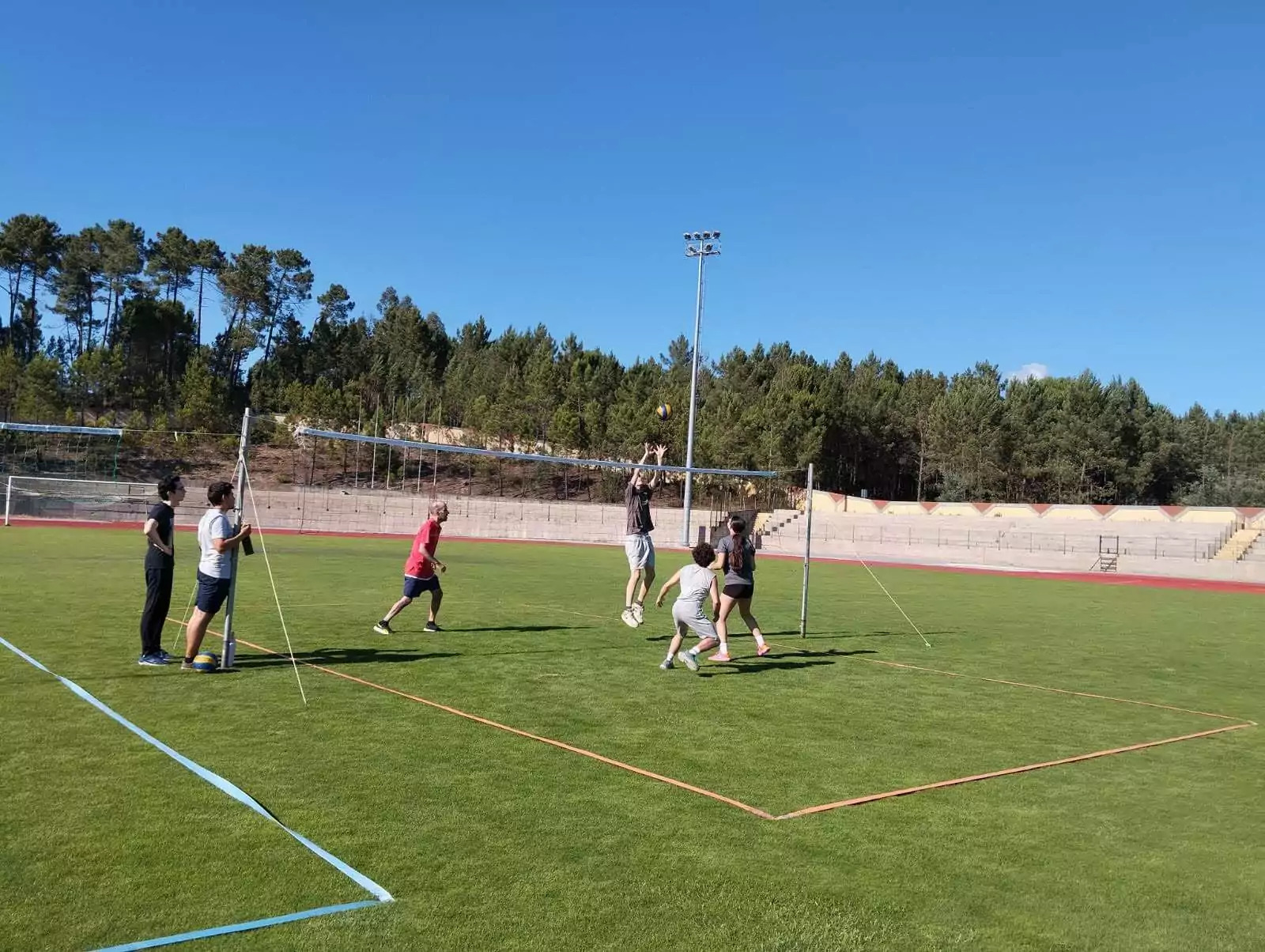 Jovens jogam voleibol no campo de relva