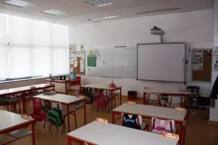Sala de aula com mesas, cadeiras, quadro e projetor