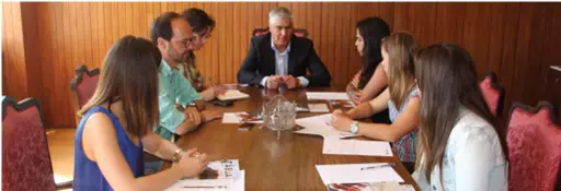 Sete pessoas reunidas à volta de uma mesa com documentos