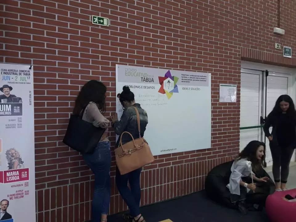Jovens consultam um painel do Projeto Educativo Local