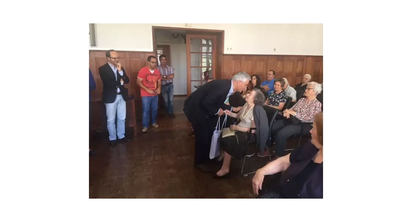 Pessoa idosa conversa com participantes numa cerimónia