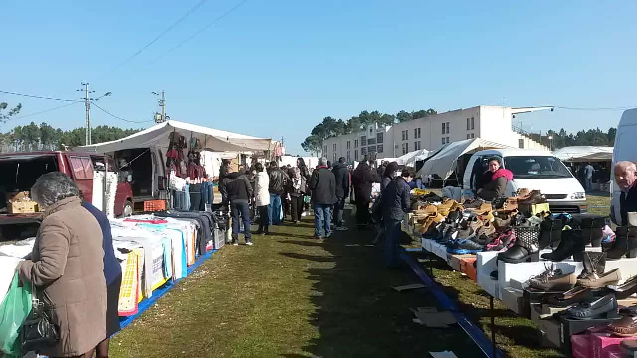 Vista geral de uma feira ao ar livre com vendedores e visitantes