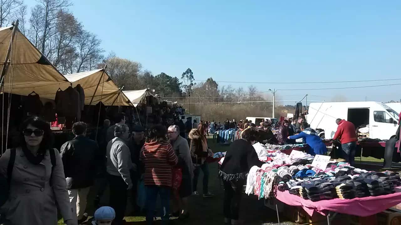 Visitantes junto a bancas de roupa na feira
