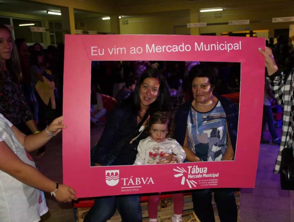 Duas mulheres e uma criança posam na moldura do Mercado Municipal