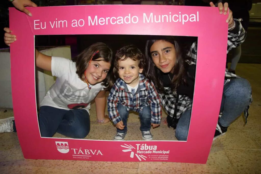Uma adolescente e duas crianças posam na moldura do Mercado Municipal