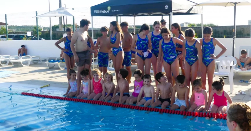 Crianças e equipa de natação junto à piscina