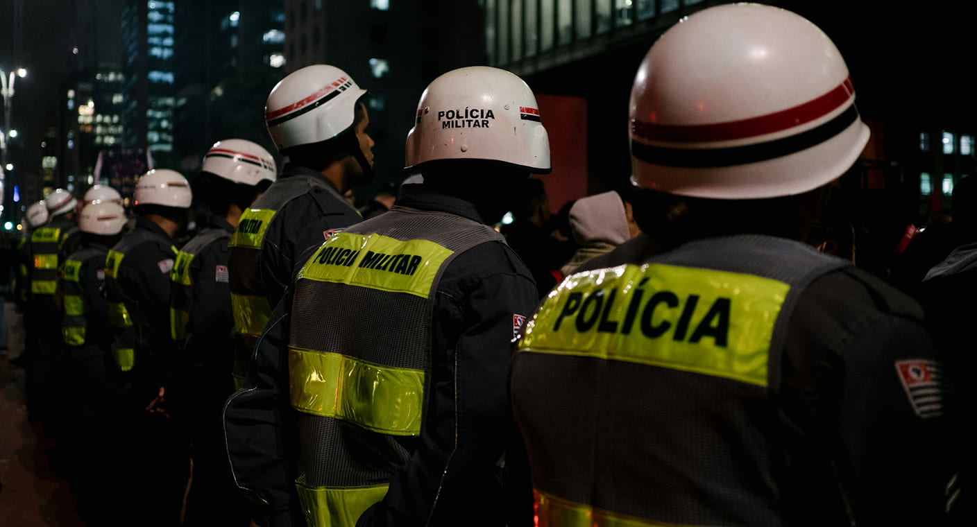 Agentes policiais vistos de costas durante uma operação