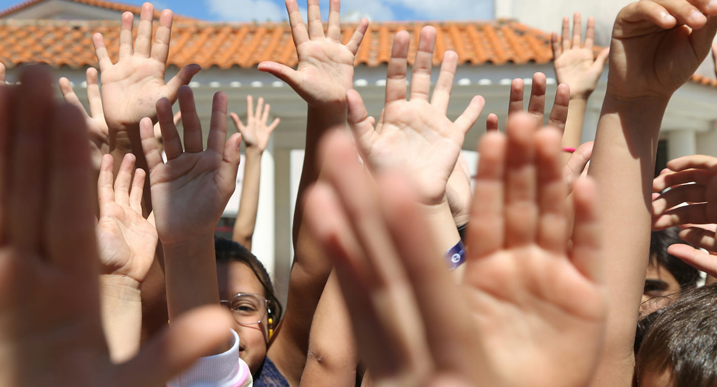 Crianças levantam as mãos durante uma atividade