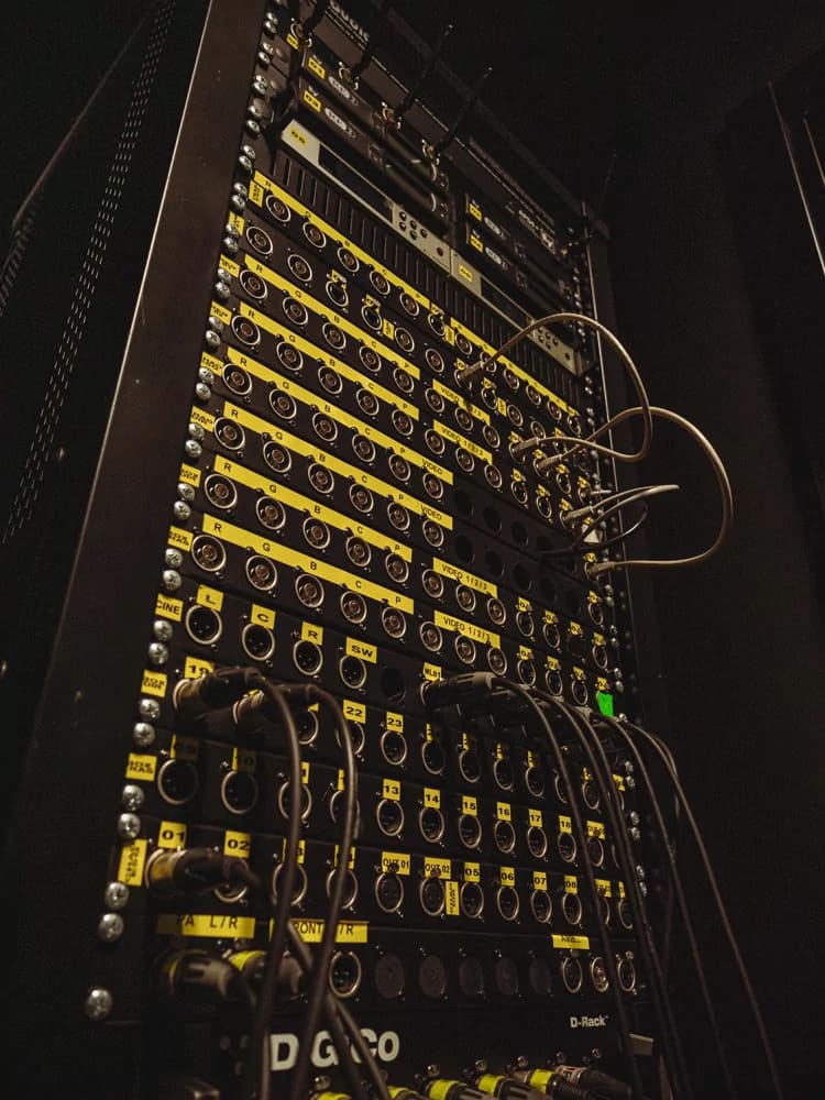 Bastidor de equipamento técnico de som e audiovisual com múltiplos cabos e ligações numeradas.