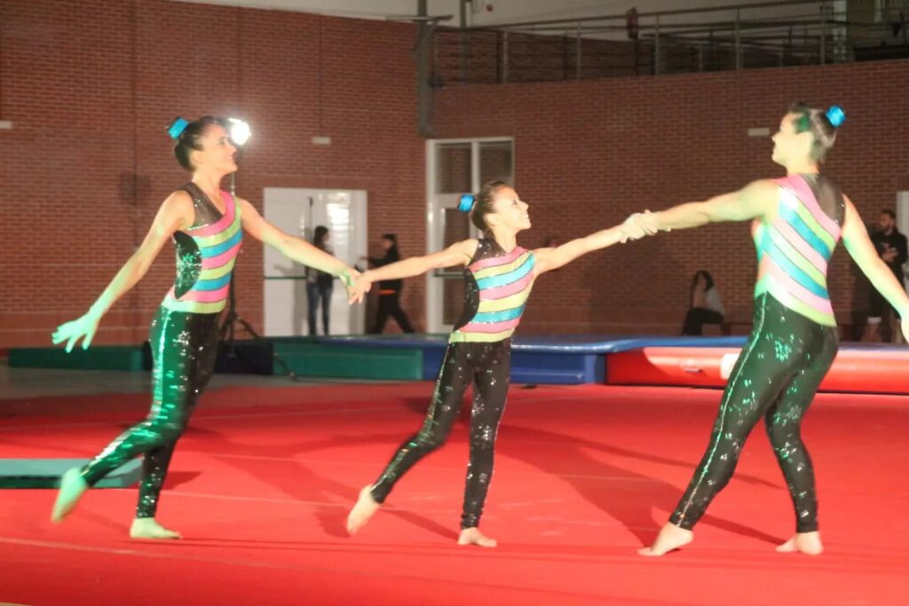 Três ginastas apresentam uma coreografia com fitas