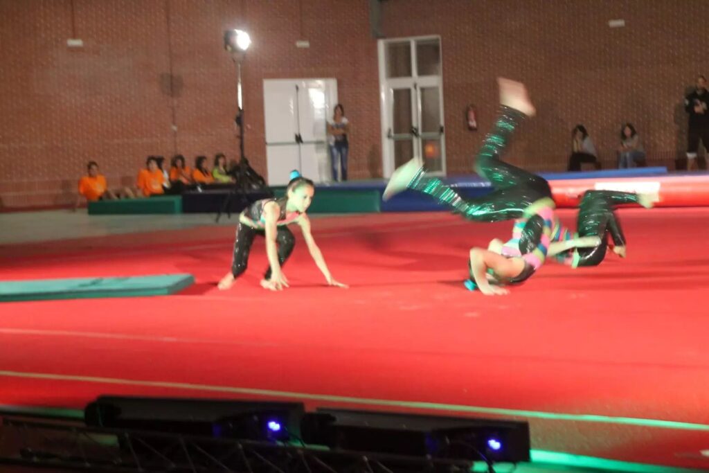 Ginastas realizam uma sequência acrobática no tapete