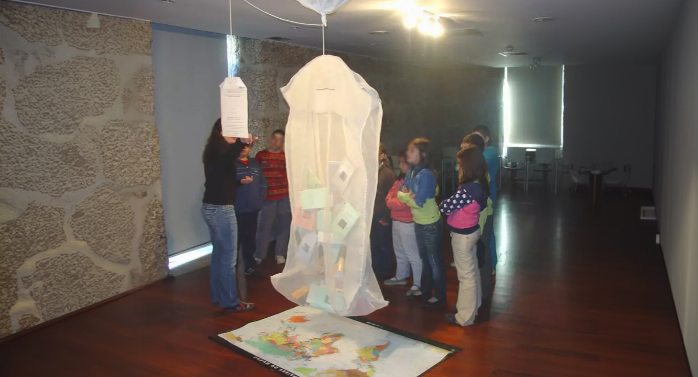 Visitantes observam uma instalação artística numa sala de pedra