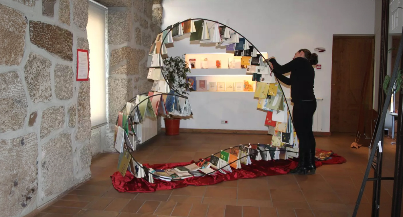 Instalação artística em forma de arco e coração composta por livros e papel
