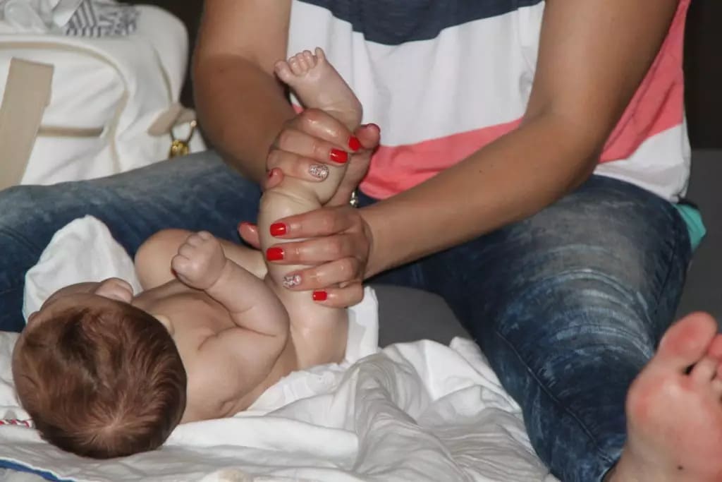 Demonstração técnica de massagem infantil na perna de um bebé durante o curso