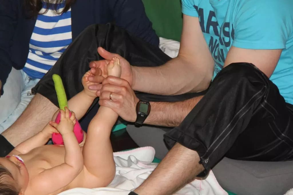 Pai a praticar técnica de toque afetuoso e massagem no pé do bebé