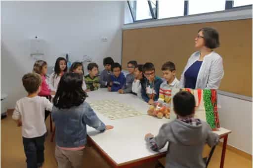 Crianças e professora reunidas numa atividade com fruta na sala de aula