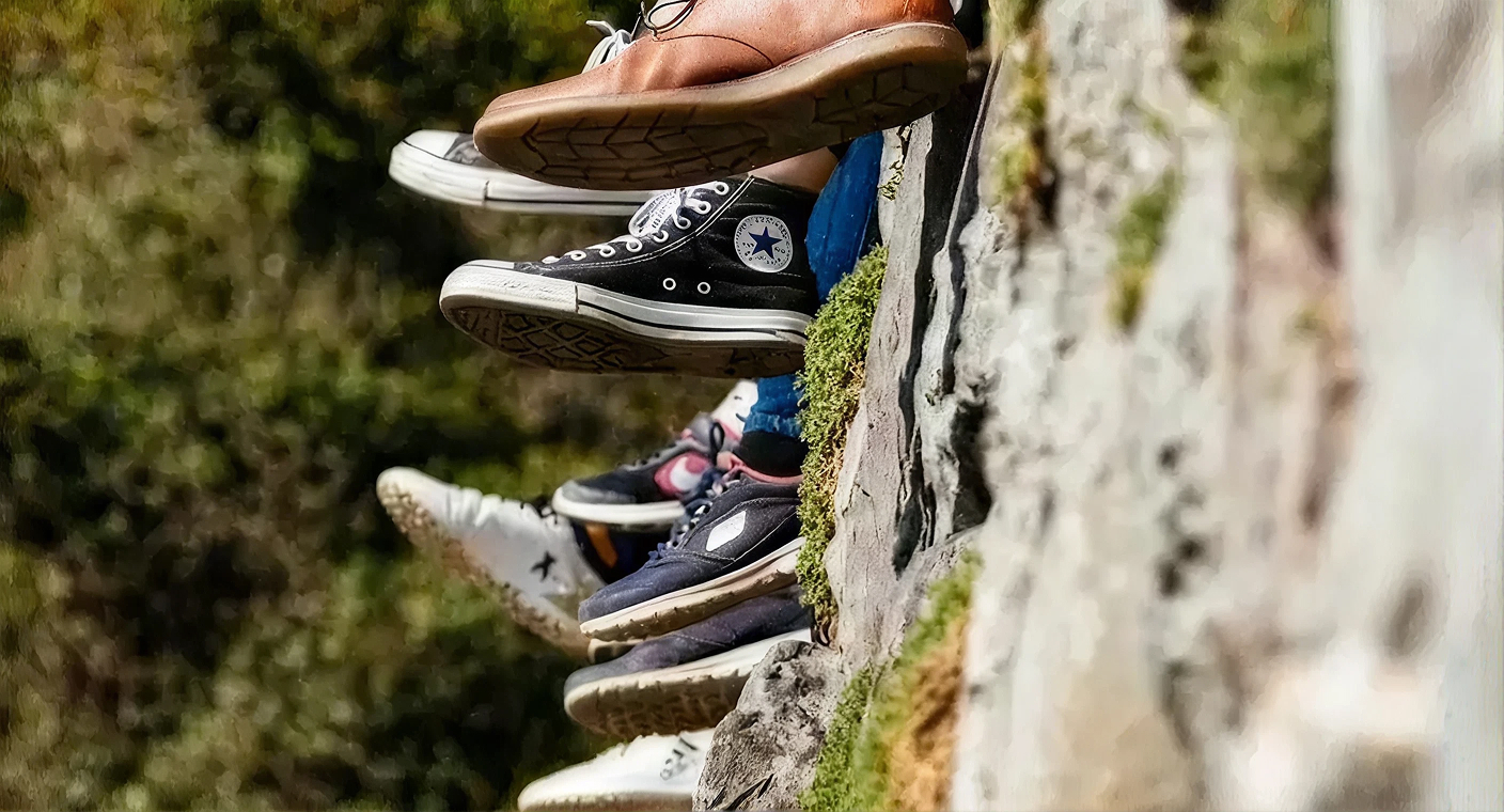 Jovens sentados num muro com os pés suspensos