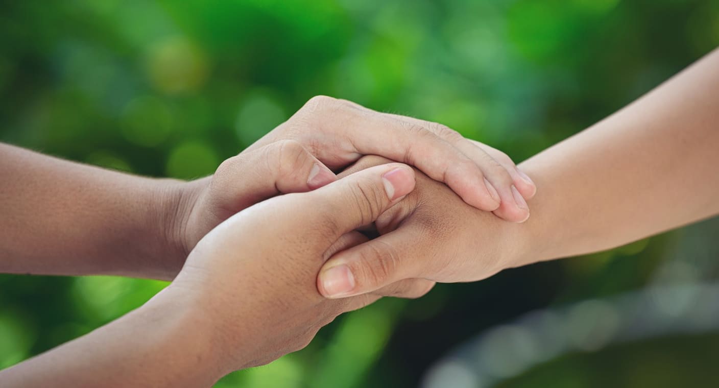 Mão de adulto segura a mão de uma criança