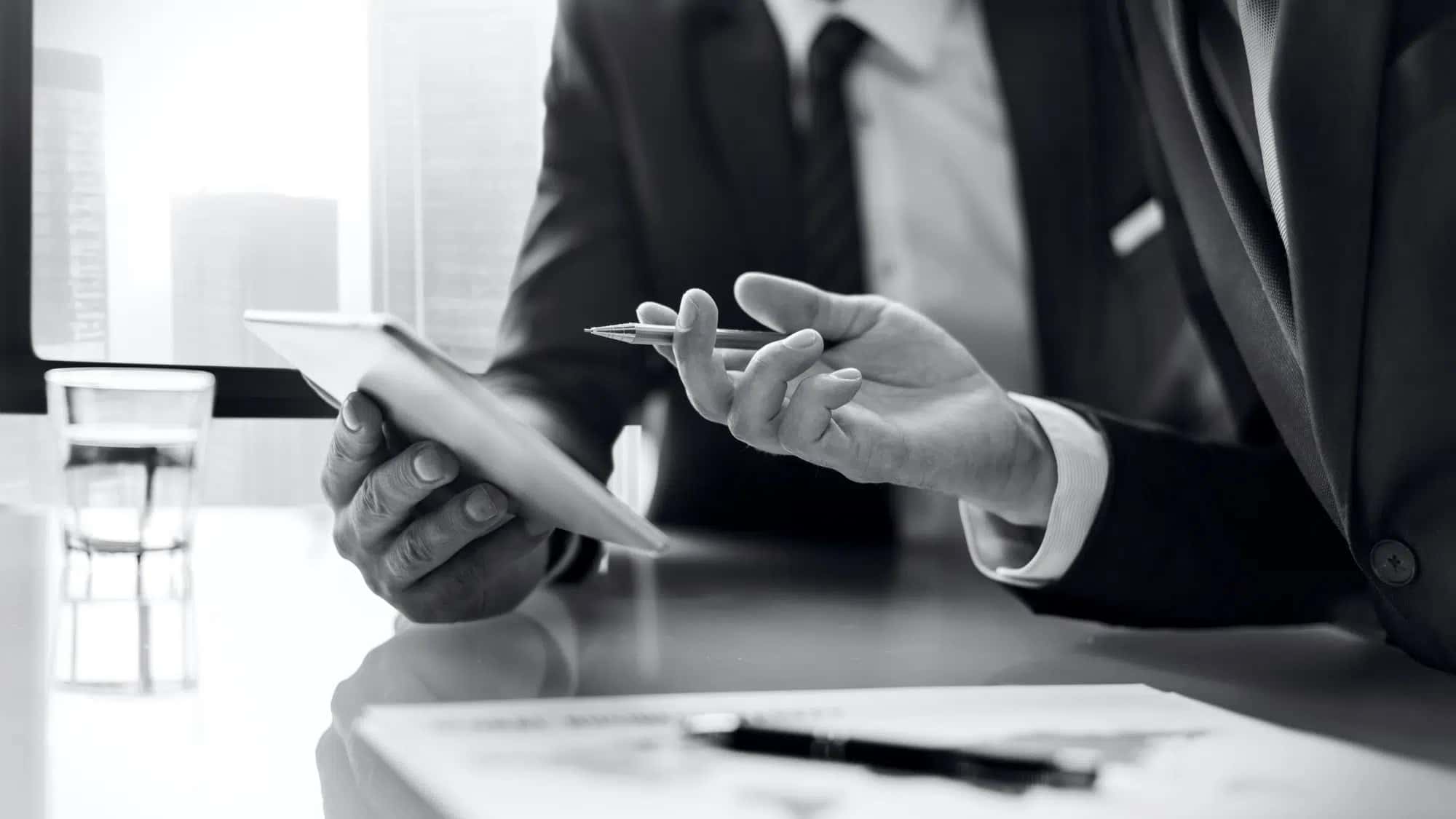 Profissionais em reunião de negócios a analisar documentos e dados num tablet.