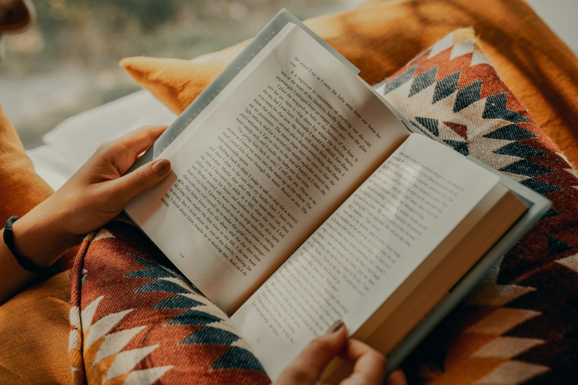 Pessoa lê um livro sentada num sofá