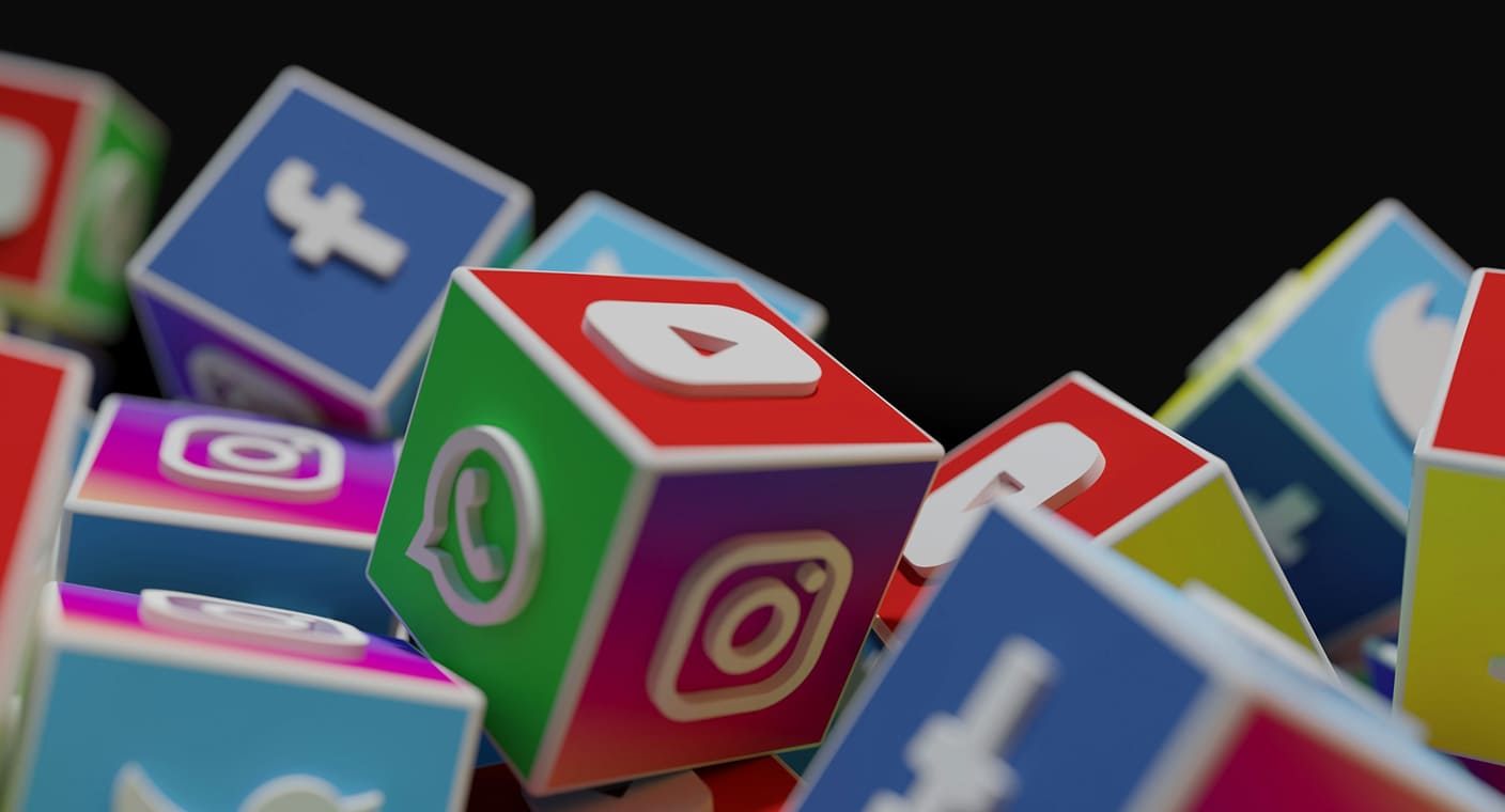 Pilha de blocos coloridos com ícones de redes sociais nas faces.